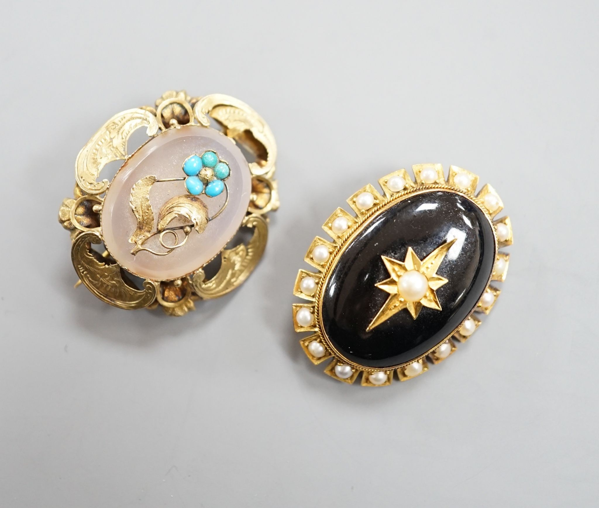 Two Victorian yellow metal and gem set oval brooches, including black enamel and split pearl, largest 34mm.